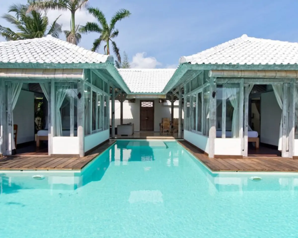 Poolside vacation-rental villa with cabanas and palm trees